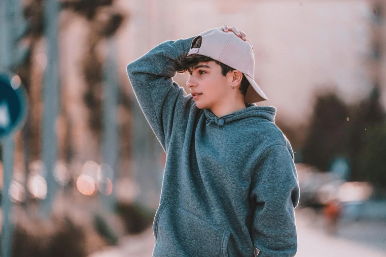 the young man is wearing a hat on the street