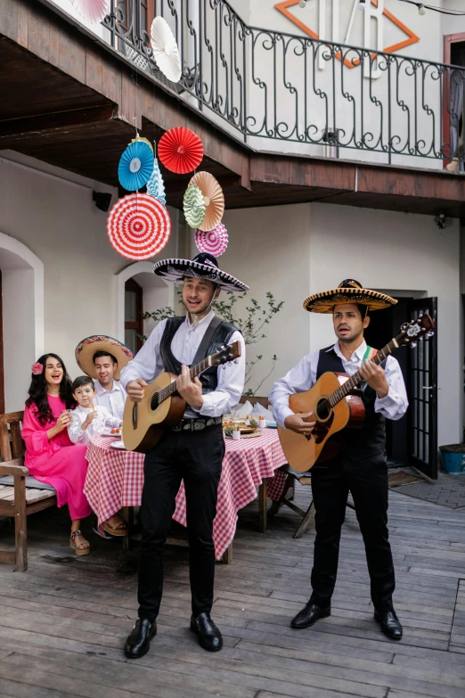 two men with mexican hats playing guitars on a patio