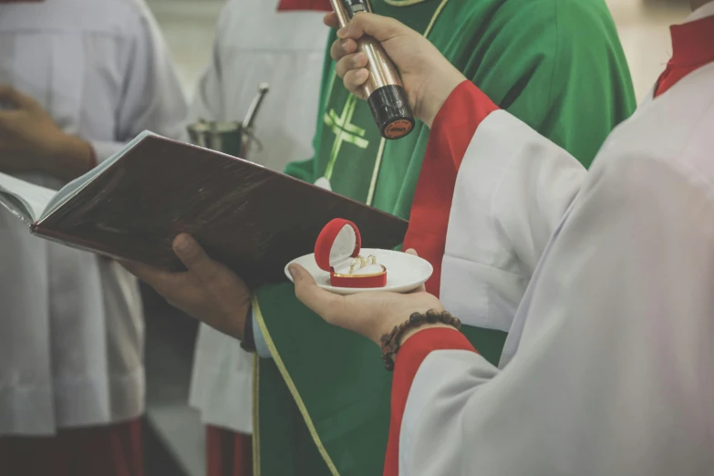 a priest holding a bible in one hand and a red ribbon on the other