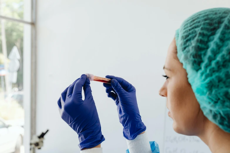 a woman in blue gloves holding a piece of plastic