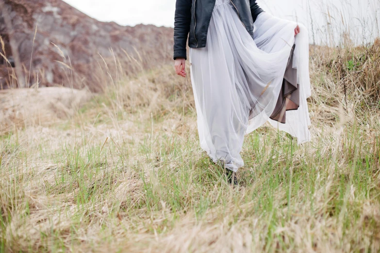 woman with long white dress walking on the grassy field