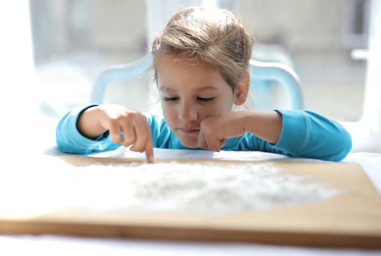 a little girl making a sand pit with her fingers