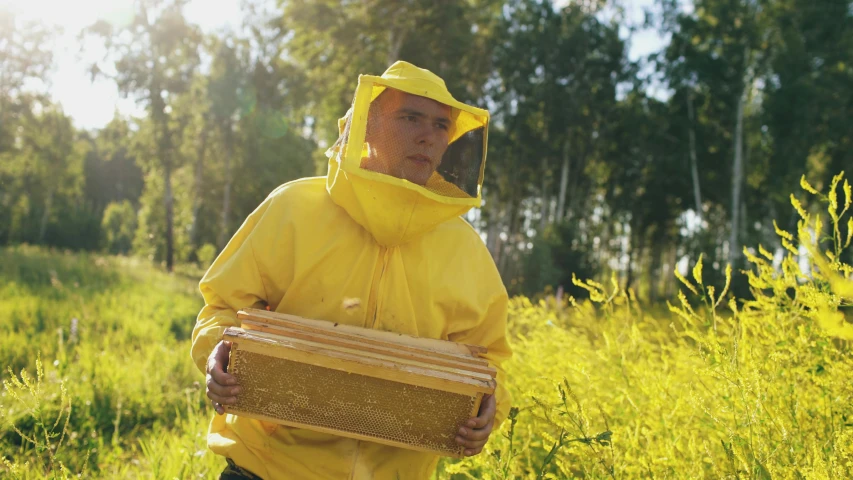 a man with a hood and a yellow jacket carrying a cooler