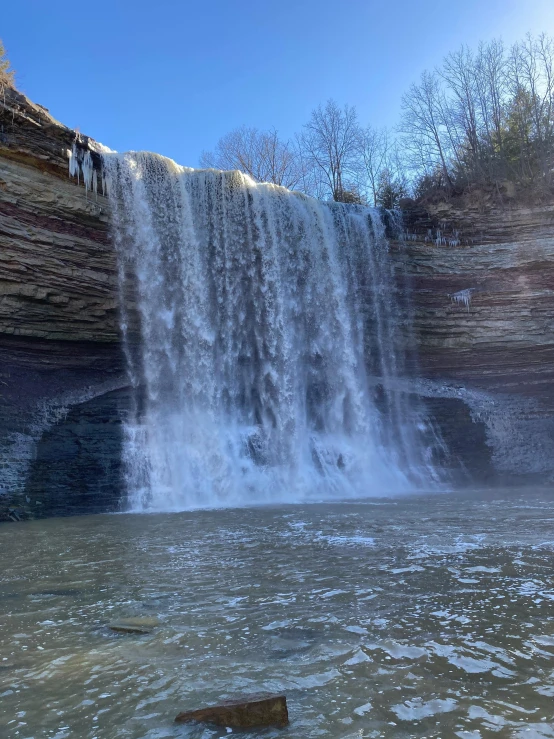 the water is gushing at the base of a waterfall