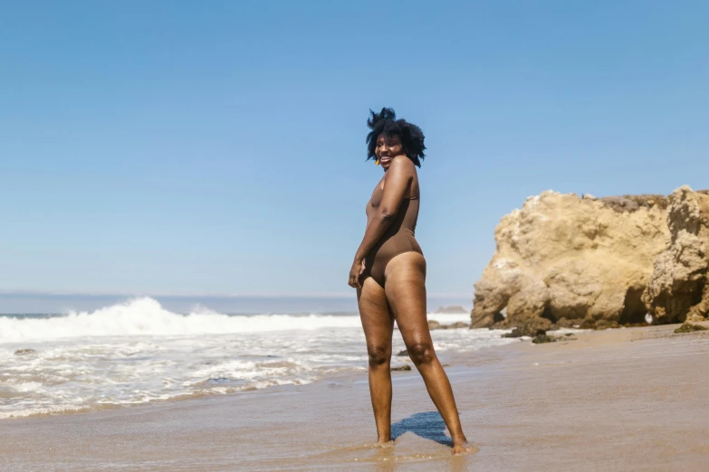 woman standing on the beach in a low cut one piece swimsuit