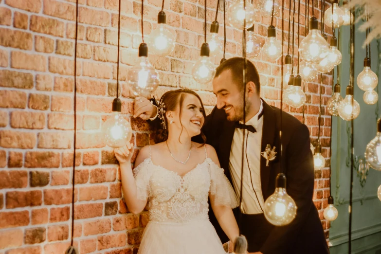 a bride and groom are in front of a brick wall