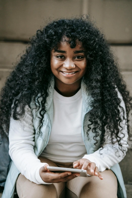 a child sitting on a step smiling holding a phone