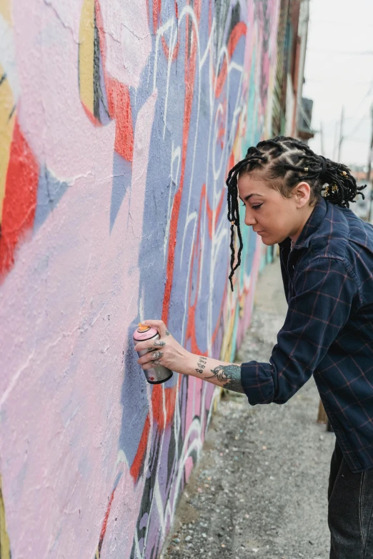 a person with dreadlocks on painting a wall