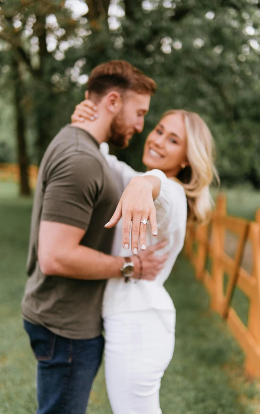 a beautiful blonde couple holding hands close together in front of a wood fence