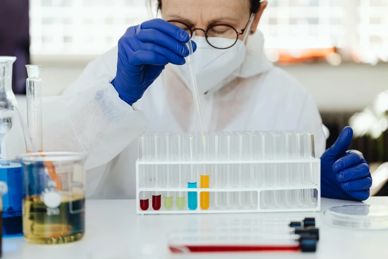 man in lab coat mixing liquids in laboratory glassware