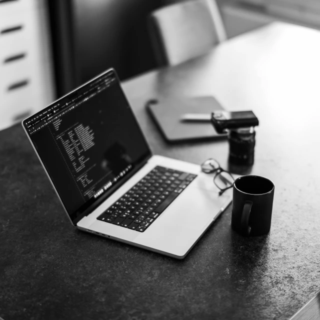 laptop computer with pen and coffee mug on table