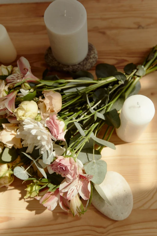 candles with flower petals and leaves on a wooden surface