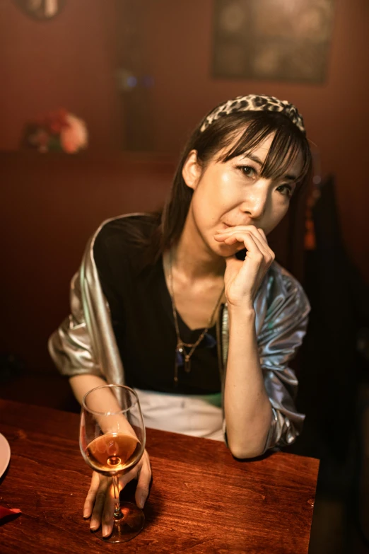 a woman sitting at a table with a glass in her hand