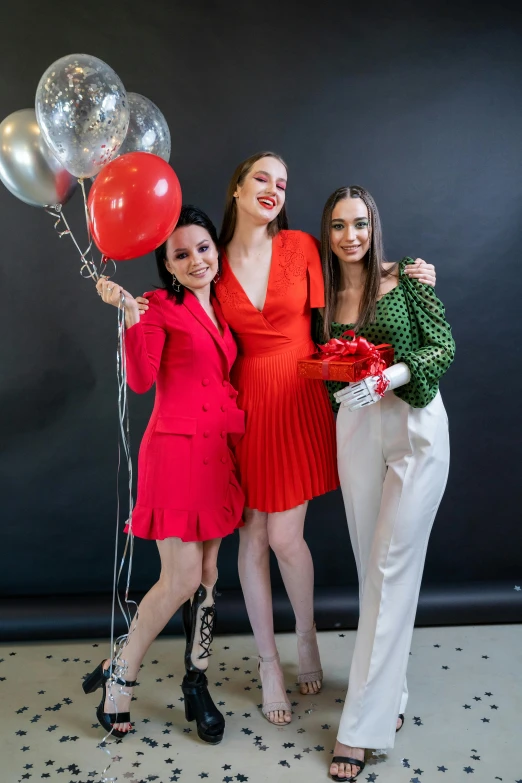 three young women holding balloons and smiling at the camera