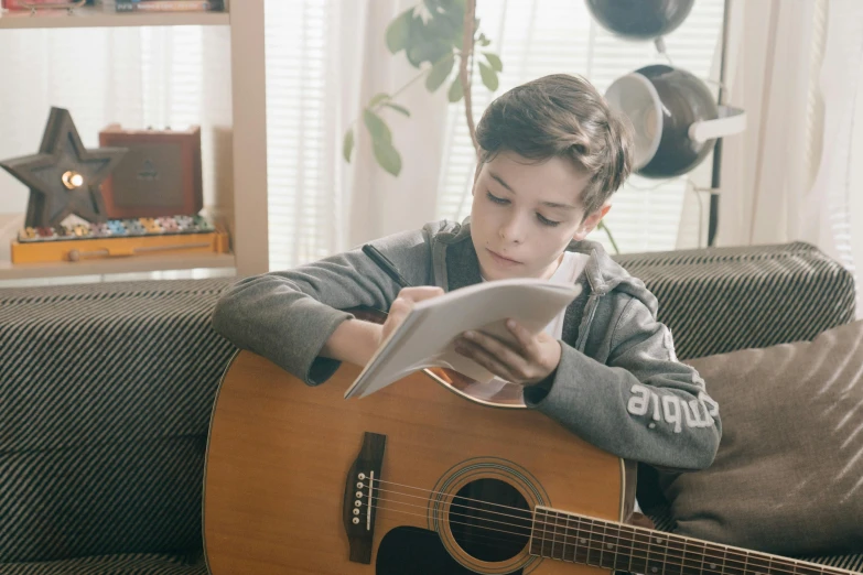  playing on guitar and reading a paper