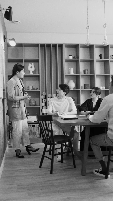 several people sitting at a wooden dining table with a book shelf in the background