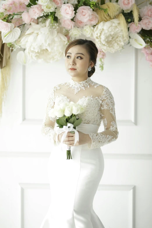 the bride poses with her bouquet of flowers in front of flowers