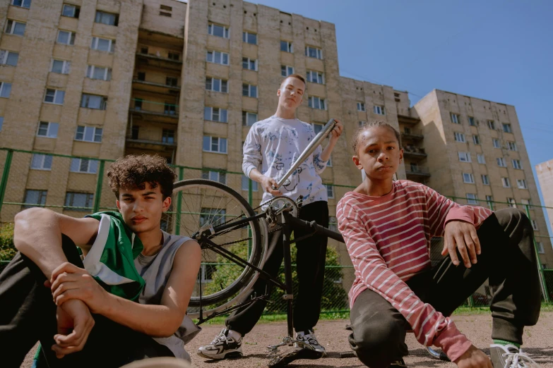 three people sit on the ground next to some bikes