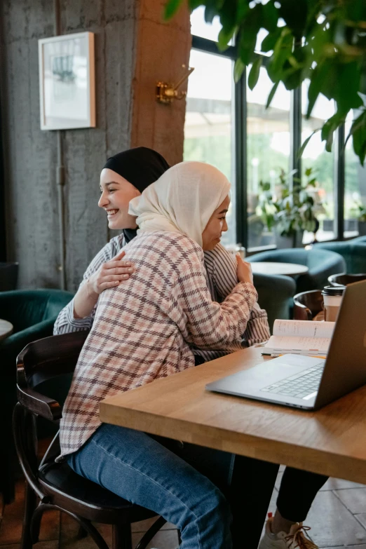 two women smiling as they sitting in an restaurant