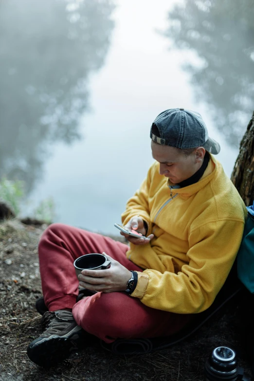 a man in a yellow jacket sits under a tree