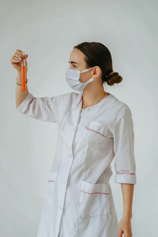 a woman in a white lab coat is holding an orange object