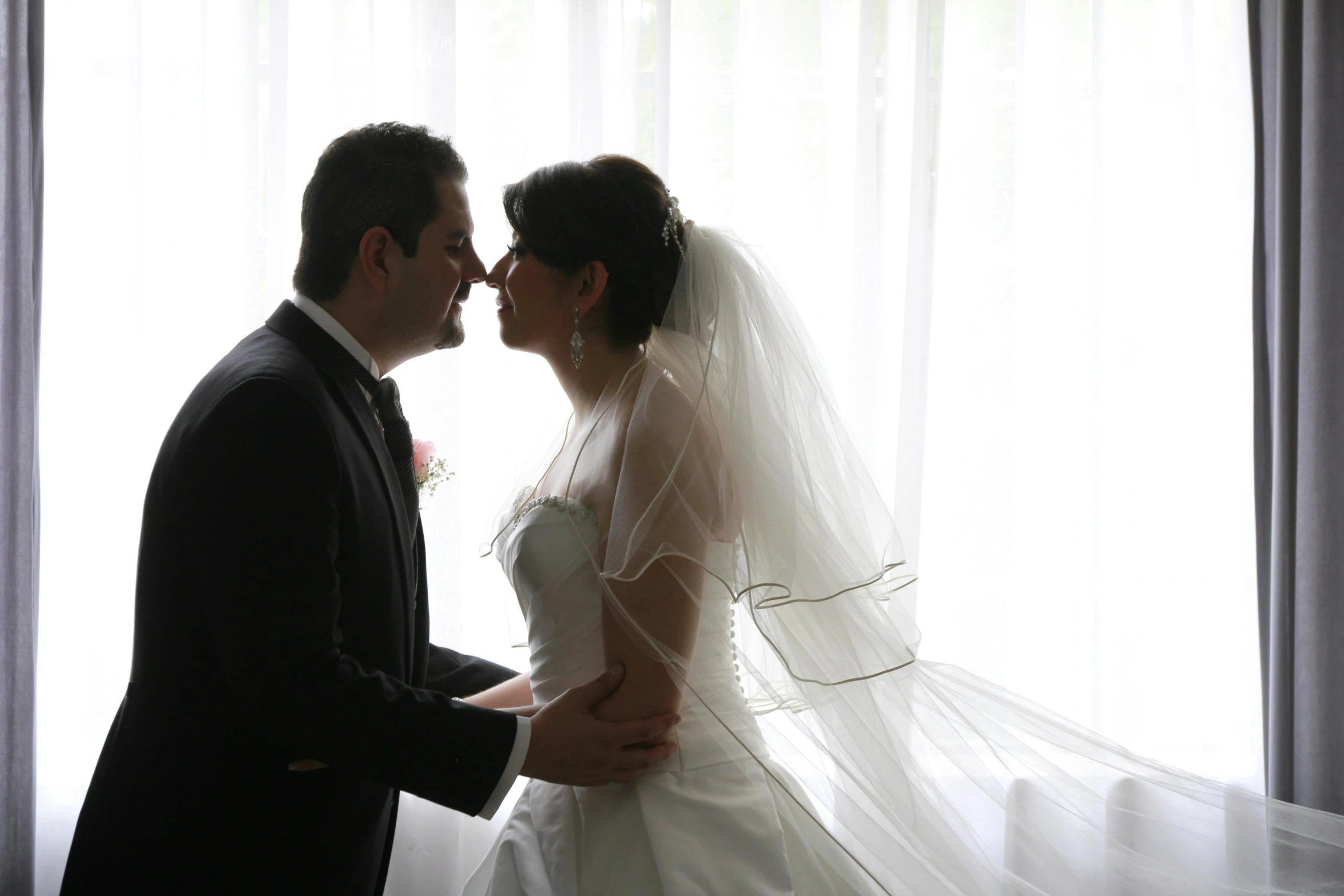 a newly married couple are kissing in front of a window
