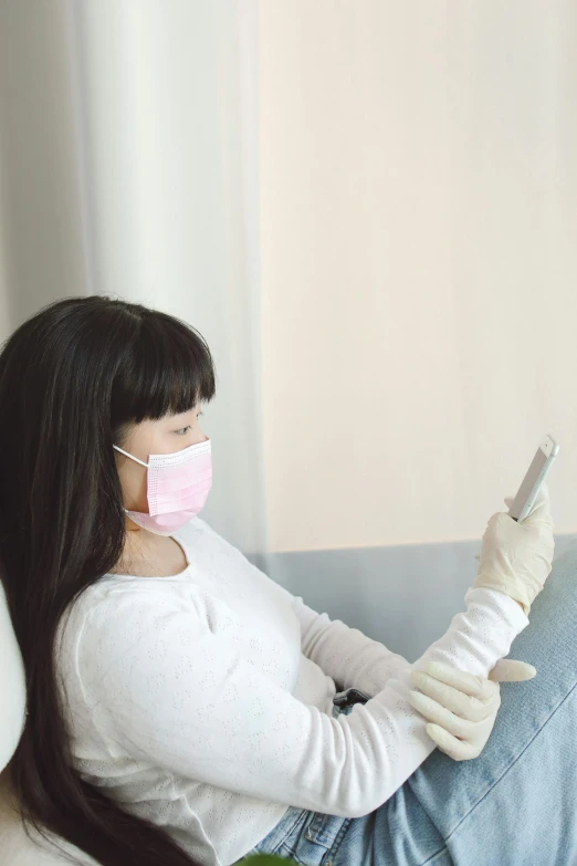 a lady sitting on the couch with her hands in medical gloves