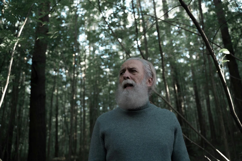 an older man standing in the middle of the woods