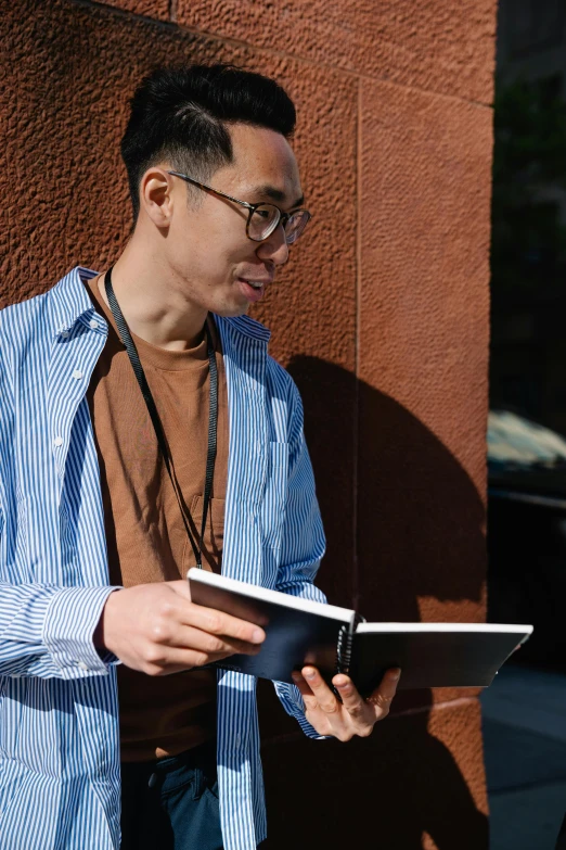 a man looking down at his tablet while standing on the side of a building