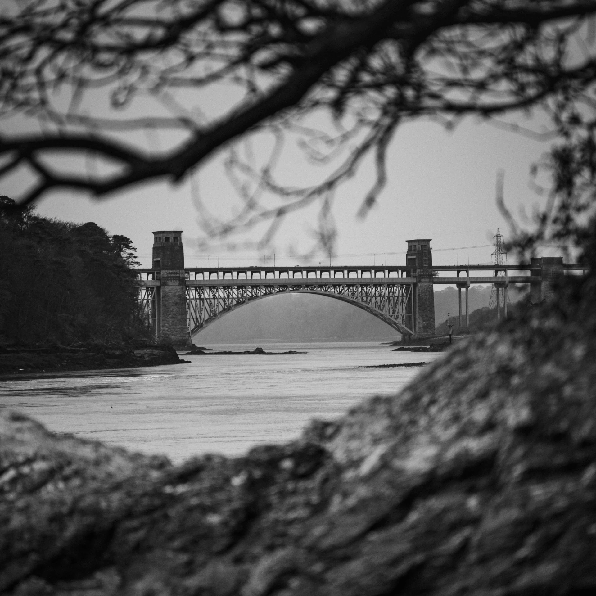 the water is calm from the current rushing underneath the bridge