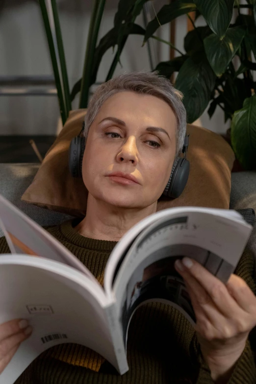 the woman is listening to music and reading a book
