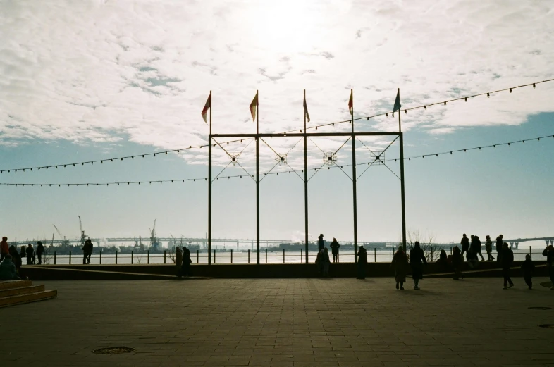 a group of people stand on a sidewalk by the water