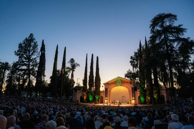 an image of crowd at the concert in front of trees