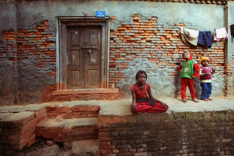 young women standing in front of a brick building with clothes drying