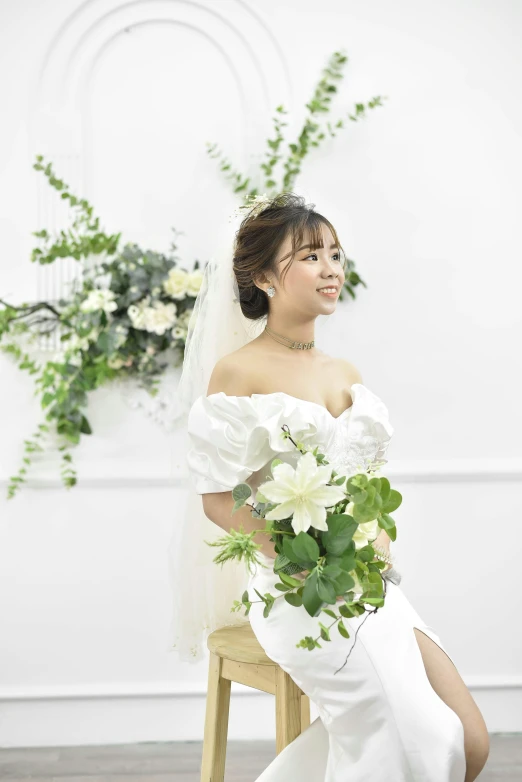 a bride holding flowers in her hands sitting on a stool