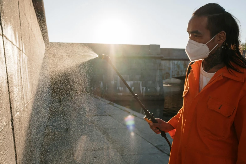 a woman with a face mask sprays water on the side of a building