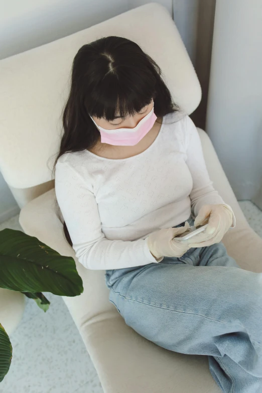 a person in a white sweater and a pink ribbon covering her mouth
