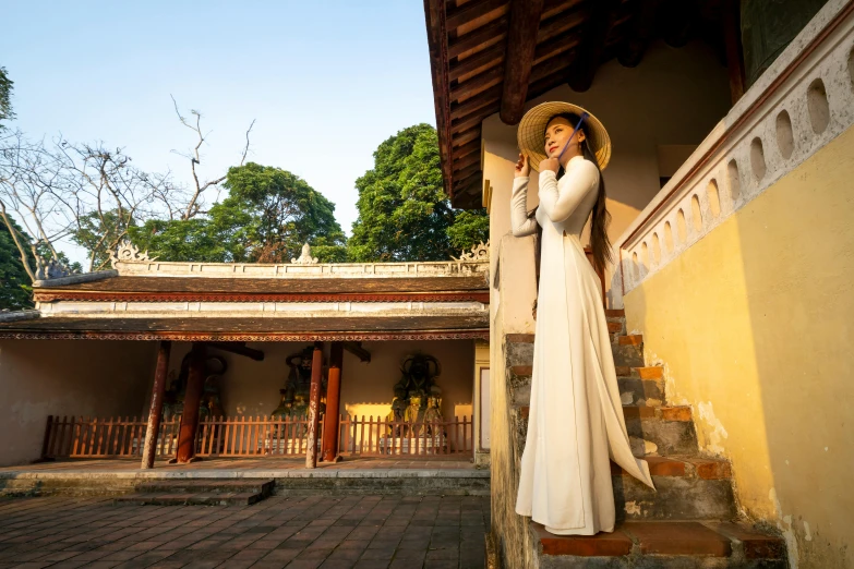 a young woman is dressed up as a long white dress and holding an umbrella