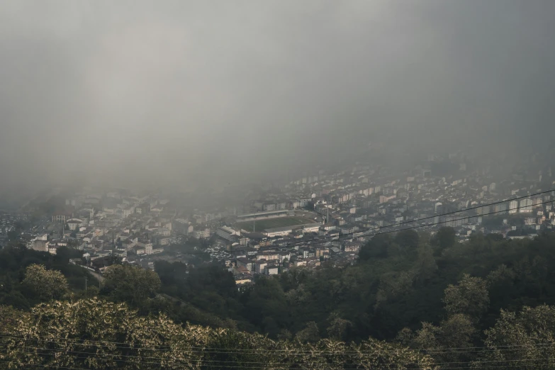 a foggy view of a village with hills and trees