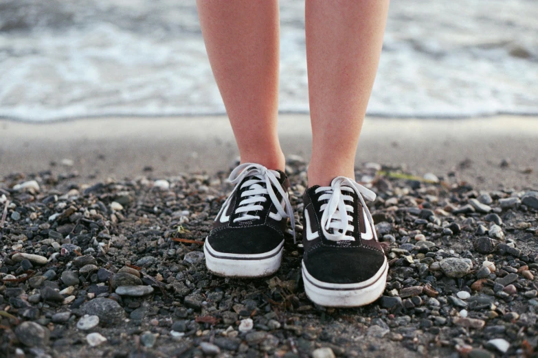 a close up of shoes on the beach by the water