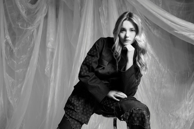 black and white image of woman sitting on stool