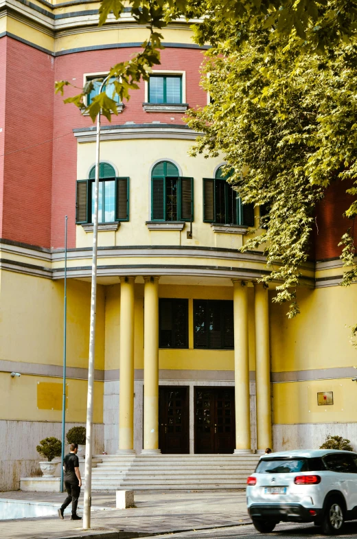 a car parked outside a building with columns and a man walking in front