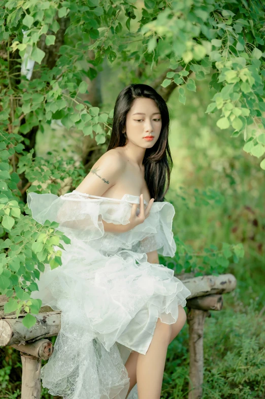 a woman is sitting on a bench under the tree