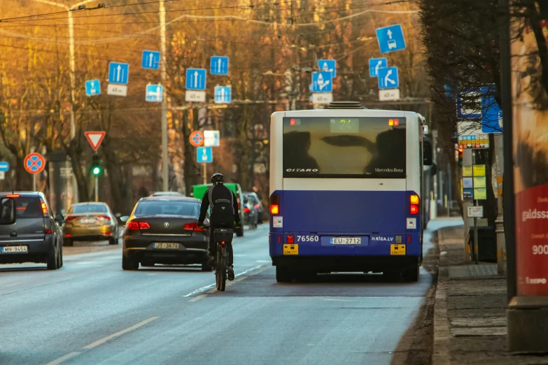 man riding a bike down a road by some cars