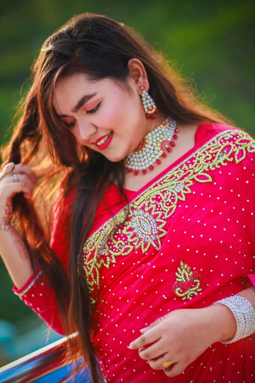 woman with red traditional dress holding up her ear