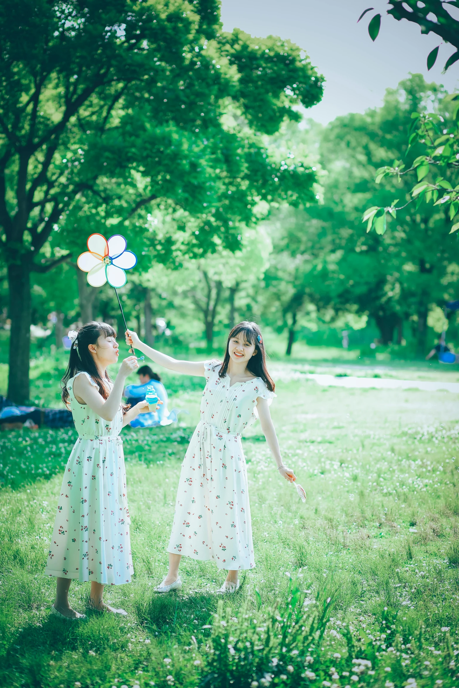 two girls holding up balloons in a park