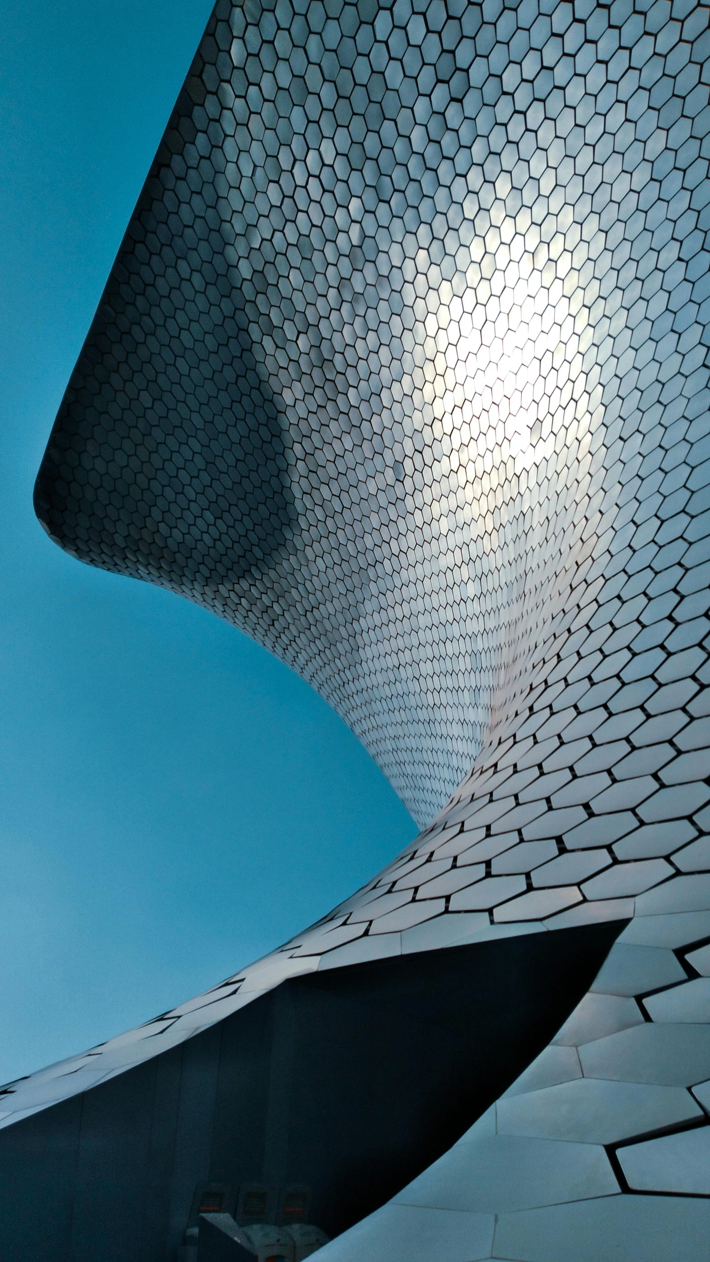 the underside view of an architectural building against a blue sky