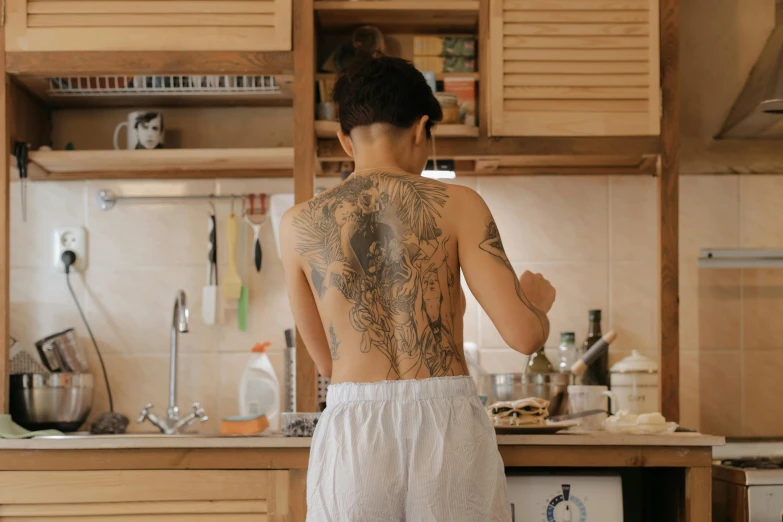 woman with tattoos in front of kitchen counter showing back