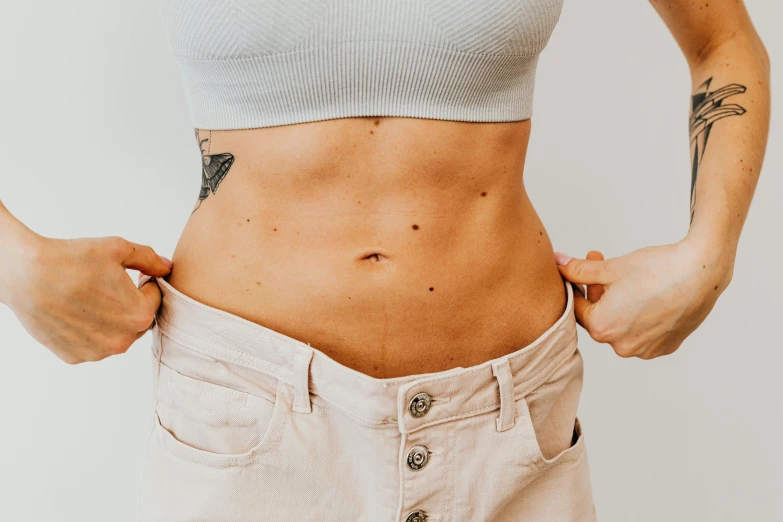 a woman showing her stomach muscles with her hands on her hips