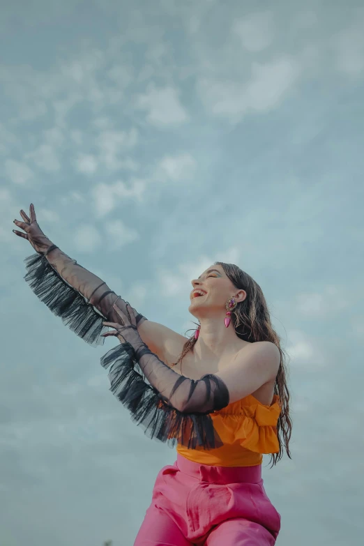 a woman in an orange top is flying her arms up